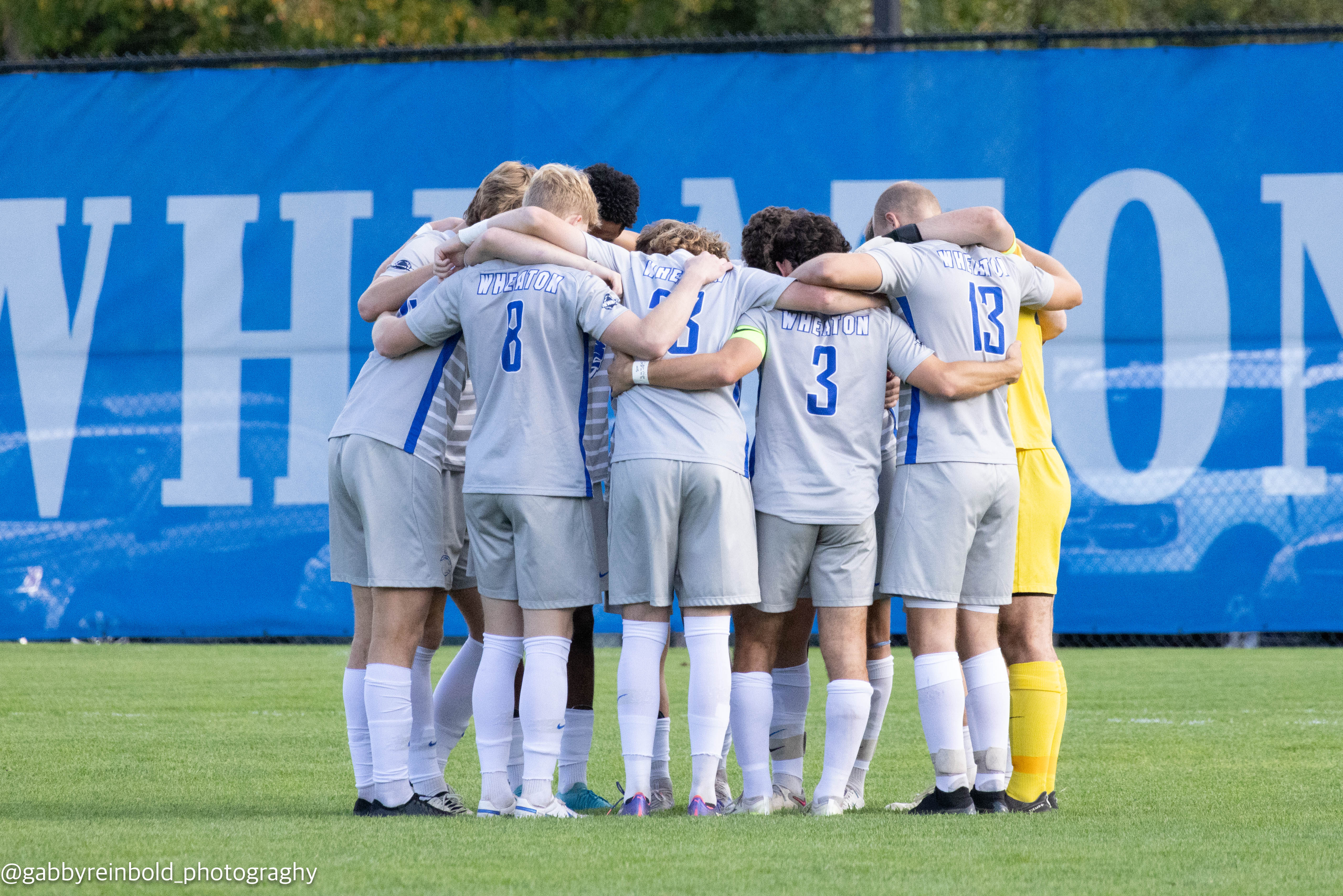 Wheaton men's soccer team starting lineup in a huddle