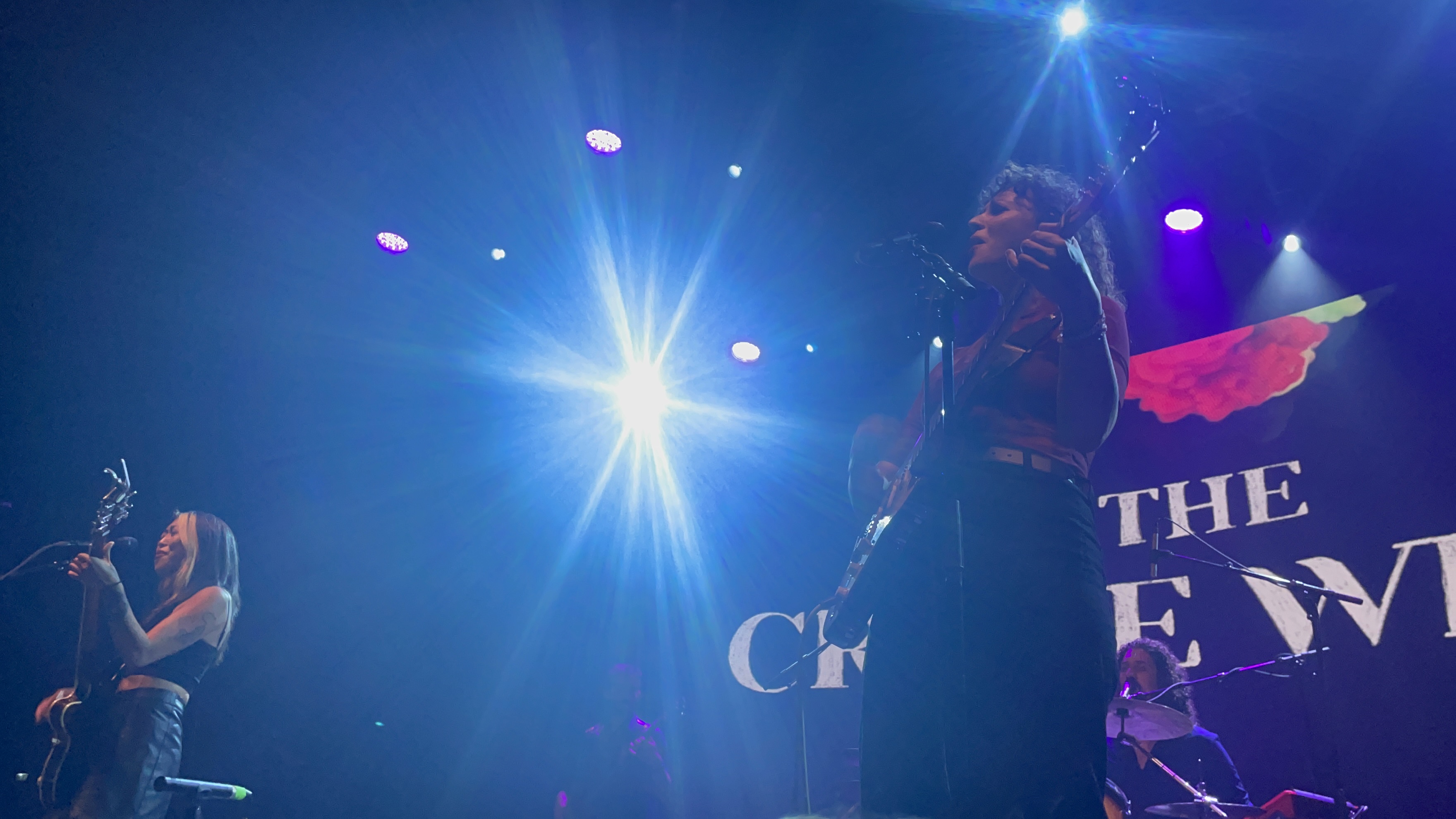 two women singing on stage while a bright blue light shines in the middle