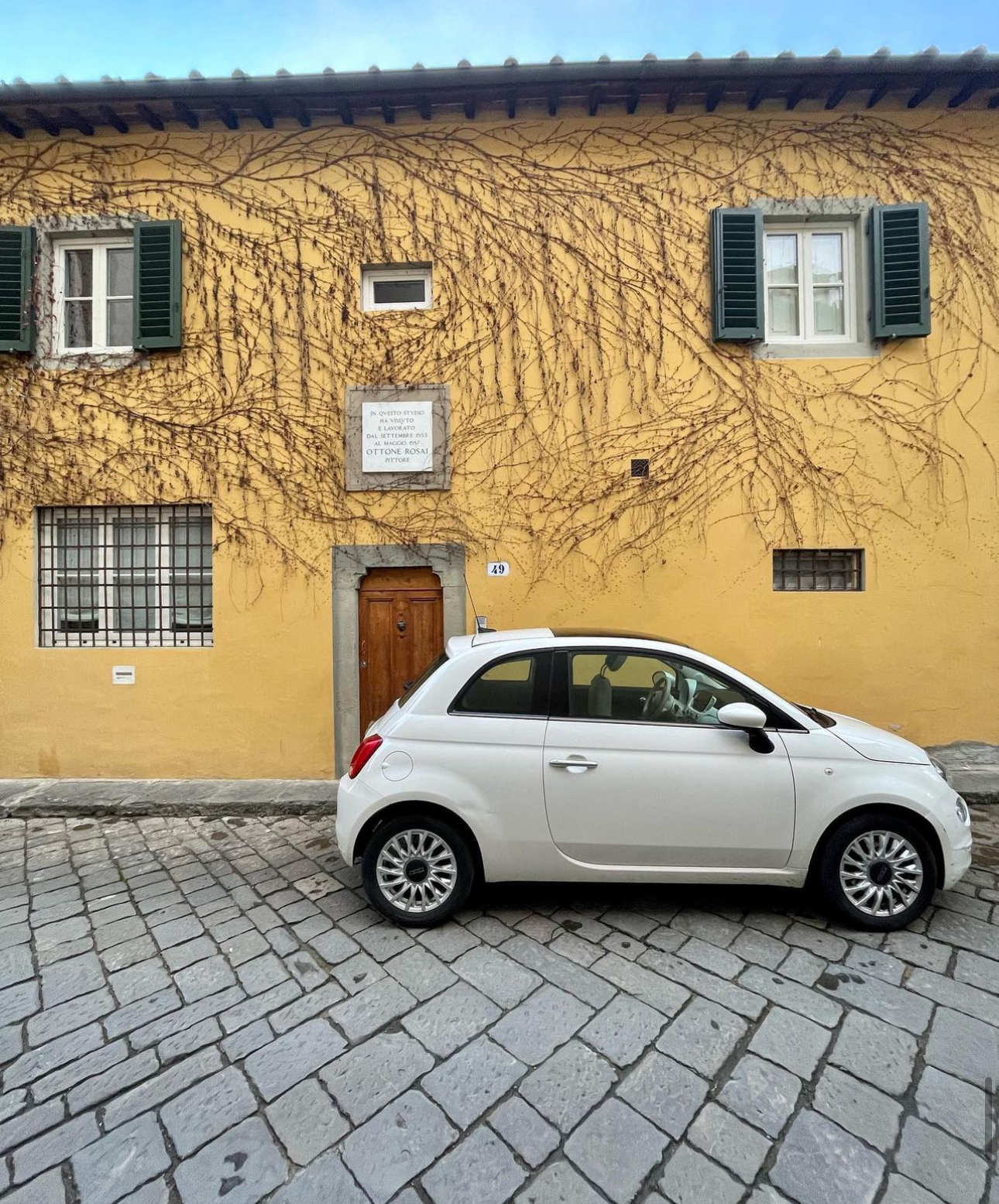 Little white car infront of yellow building